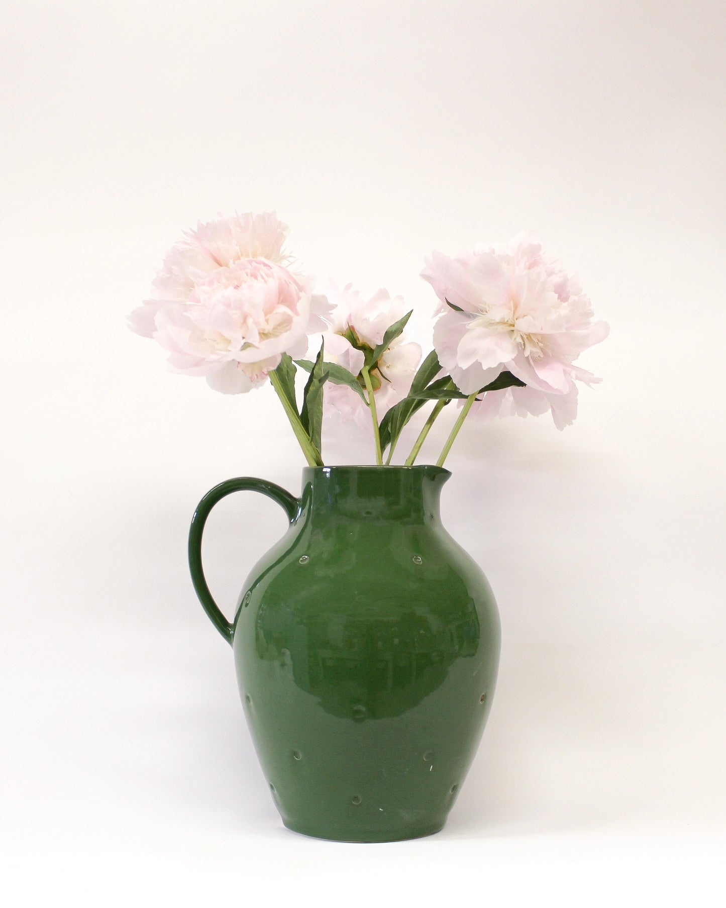 Green pitcher with pink flowers on a white background from Mima Ceramics by Michelle Organ.