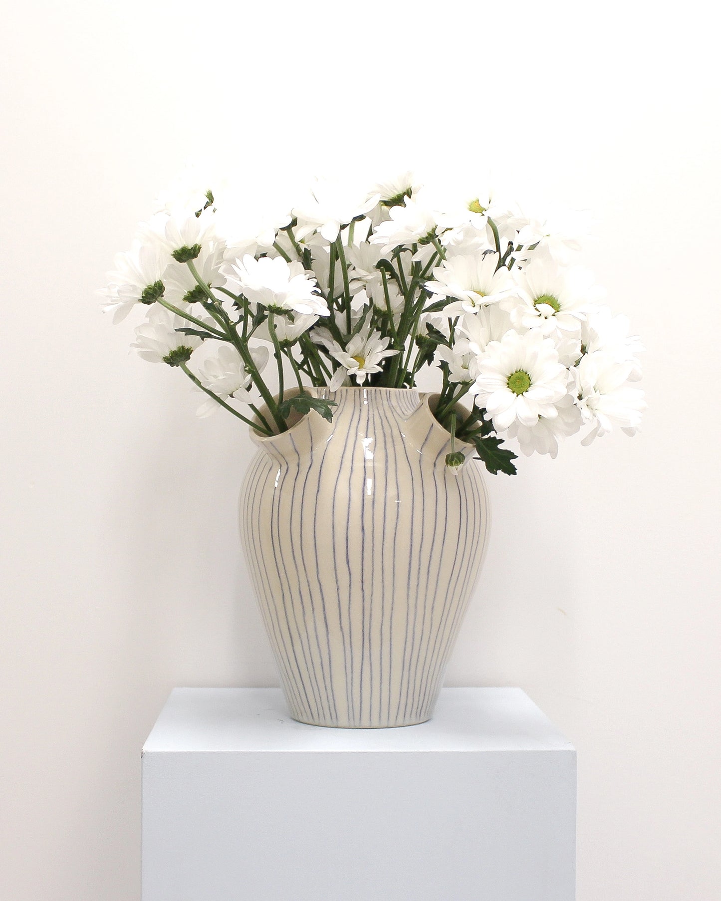 Handmade Ceramic Striped vase with white flowers on a white surface and background from Mima Ceramics by Michelle Organ.