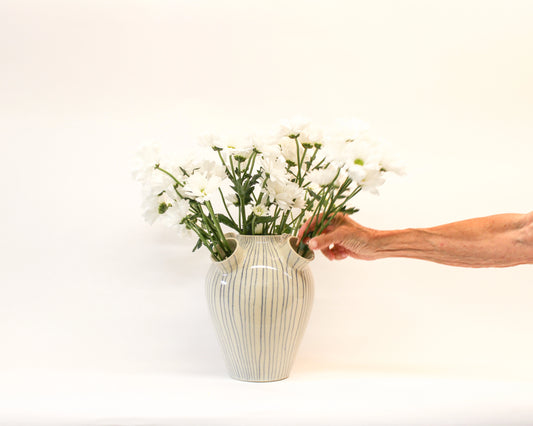 Person arranging flowers in a handmade wheel thrown white vase with blue stripes from Mima Ceramics by Michelle Organ. 