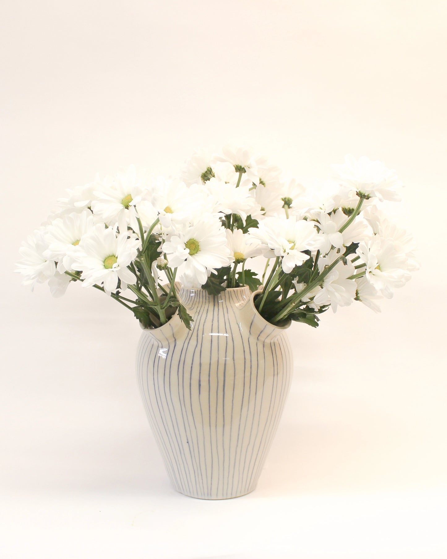 Handmade White Ceramic vase with Blue Stripes with striped pattern holding white flowers from Mima Ceramics by Michelle Organ. 