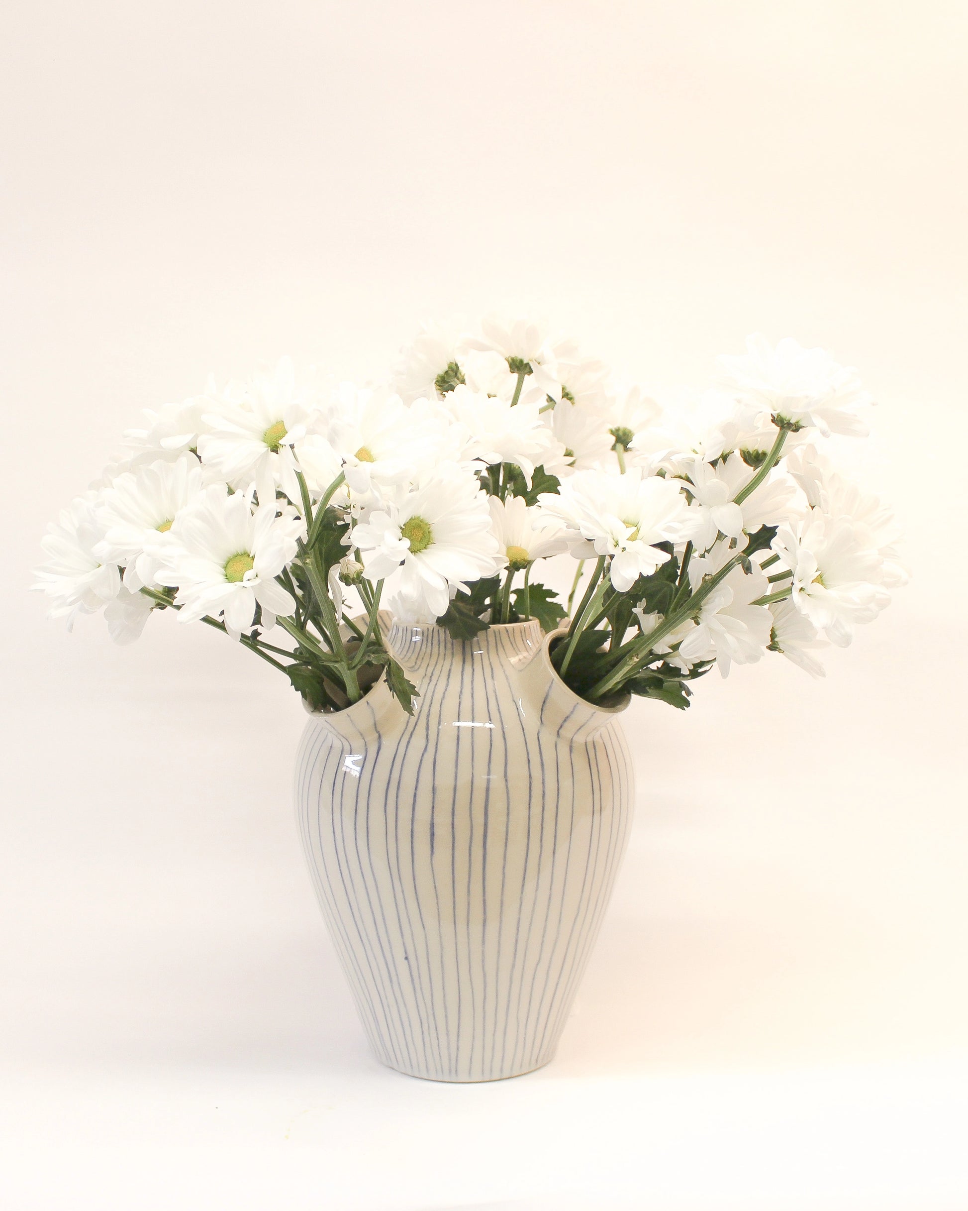 Handmade White Ceramic vase with Blue Stripes with striped pattern holding white flowers from Mima Ceramics by Michelle Organ. 