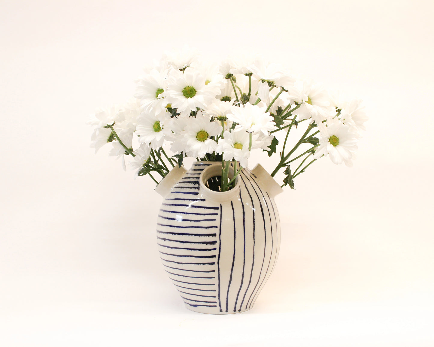 Handmade Ceramic Striped vase with white flowers on a white background from Mima Ceramics by Michelle Organ. 