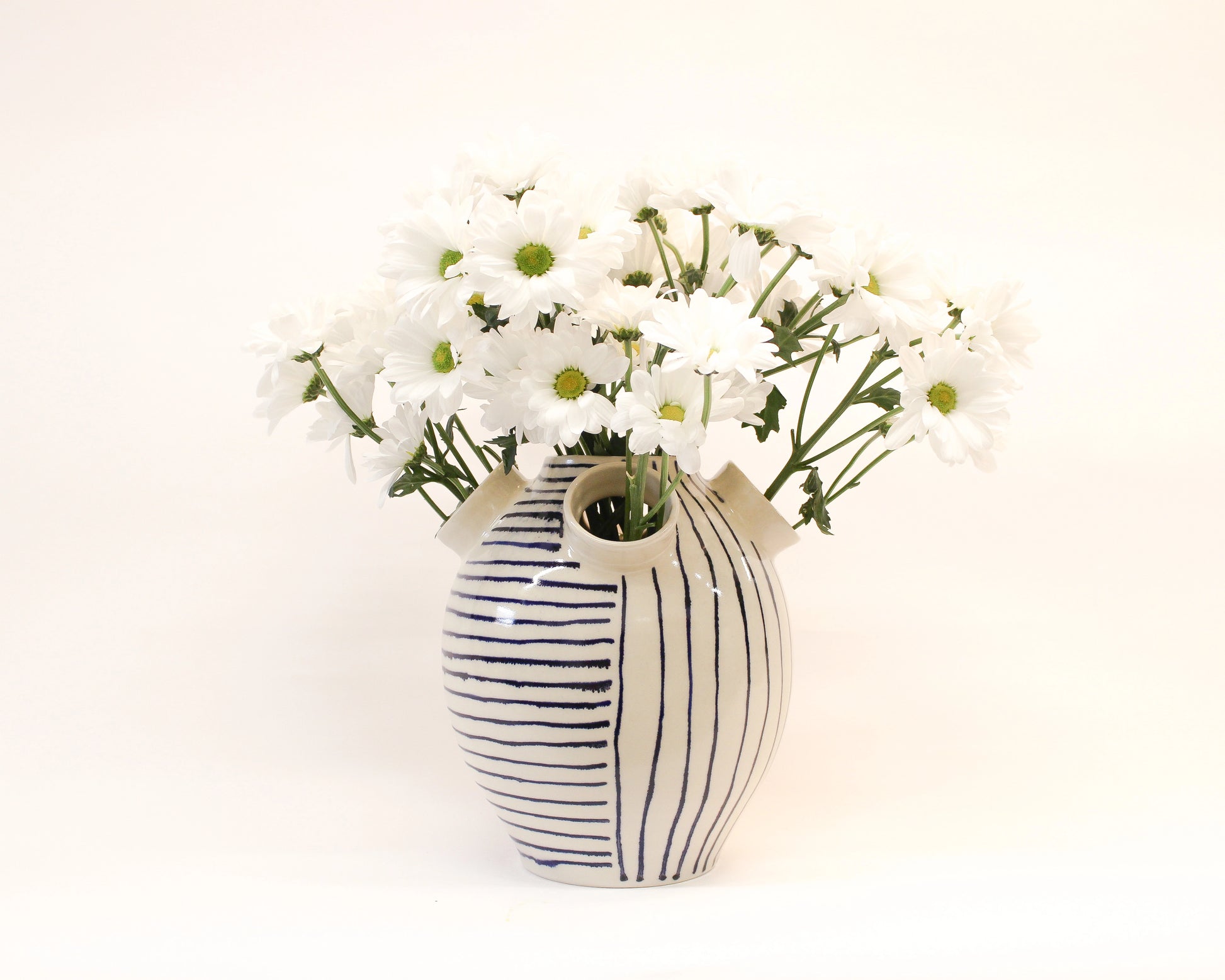 Handmade Ceramic Striped vase with white flowers on a white background from Mima Ceramics by Michelle Organ. 
