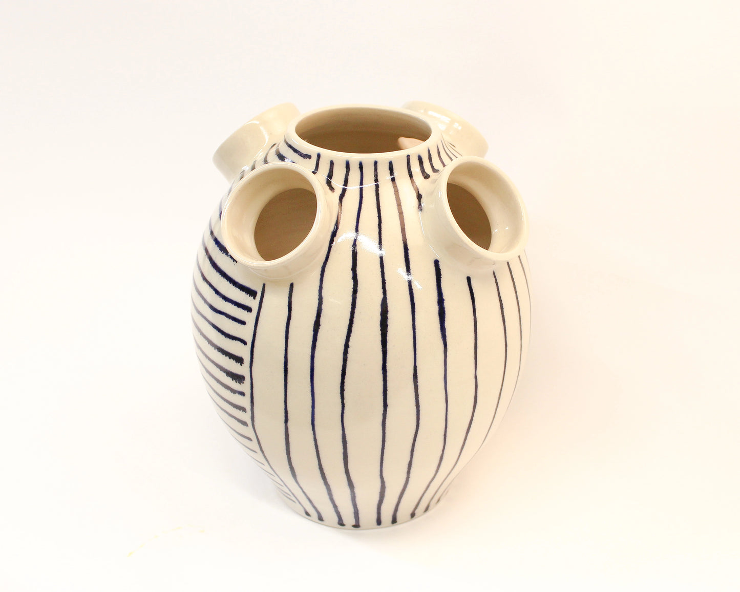 Handmade Ceramic vase with blue stripes and three circular holes on a white background from Mima Ceramics by Michelle Organ. 
