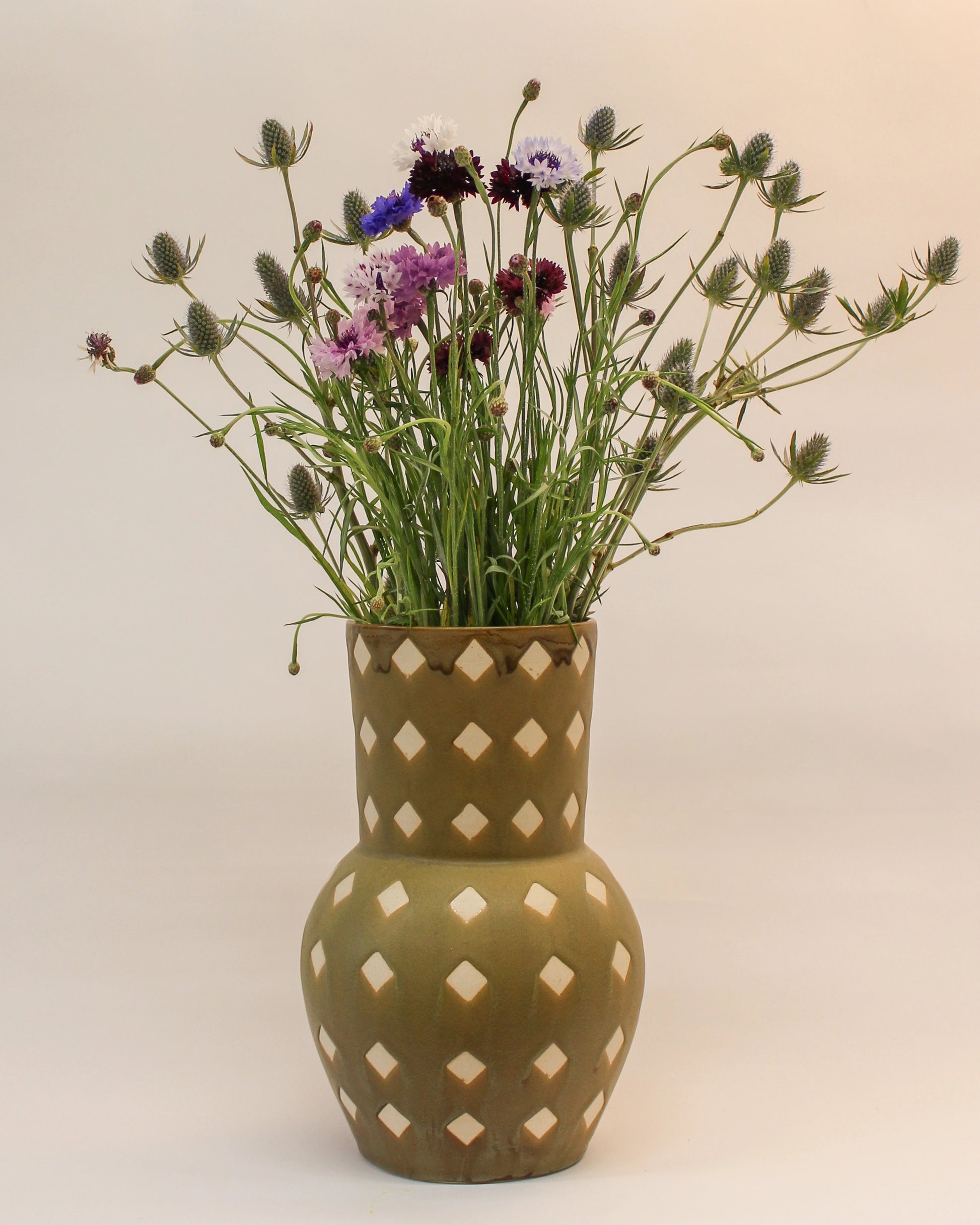 Decorative Handmade Ceramic  vase with diamond patterns filled with wildflowers on a plain background from Mima Ceramics by Michelle Organ.
