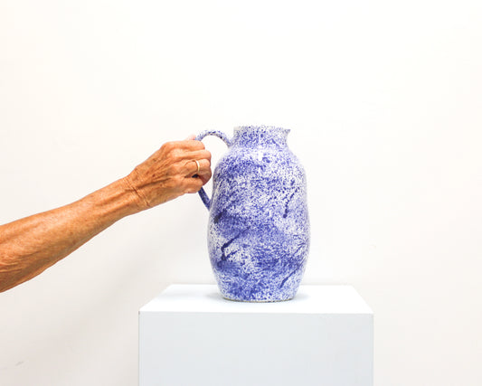 Hand holding a handmade blue and white ceramic pitcher from Mima Ceramics by Michelle Organ.